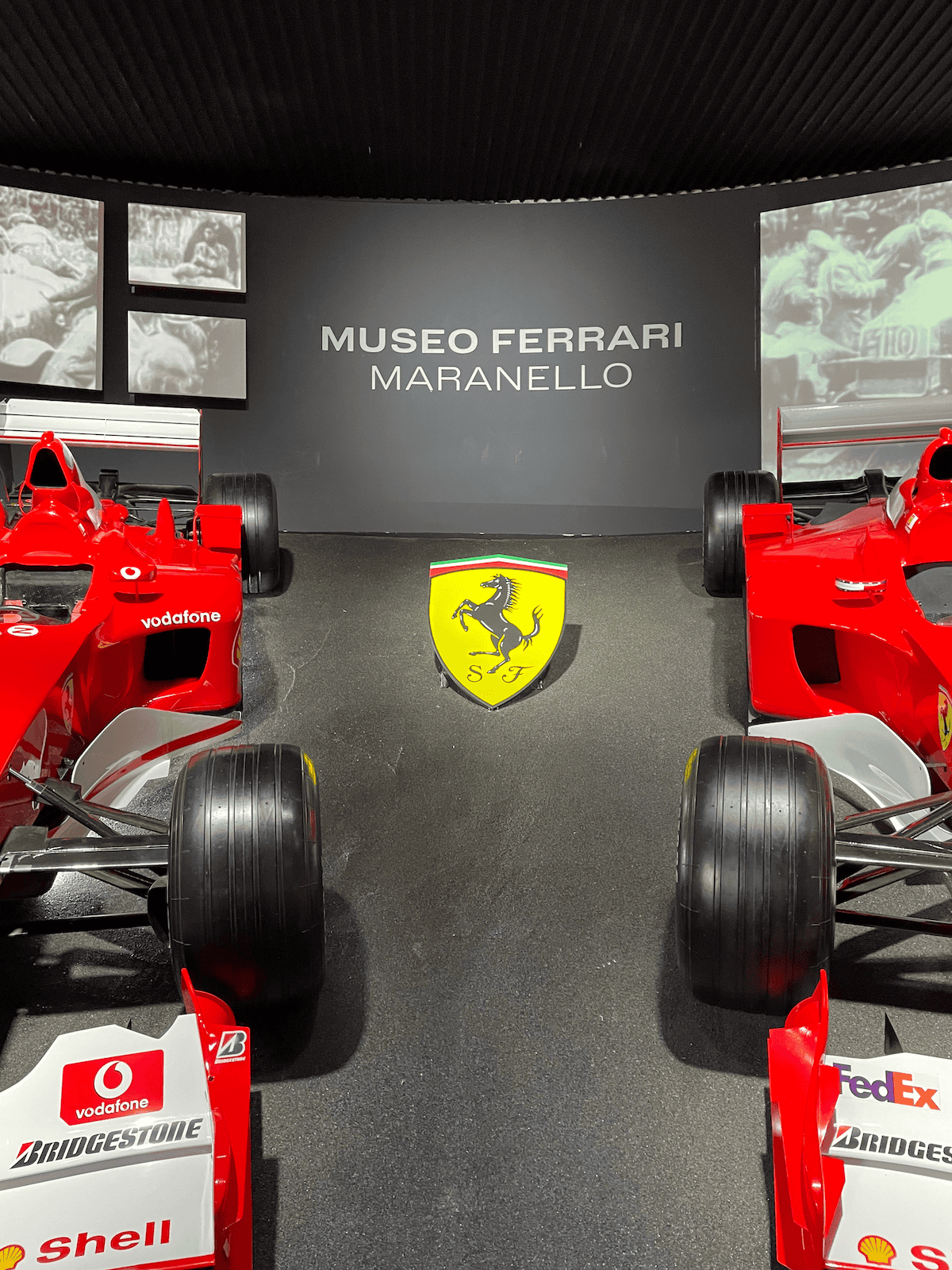 two ferrari F1 cars and the words 'museo ferrari maranello' on the wall with the ferrari logo in the middle