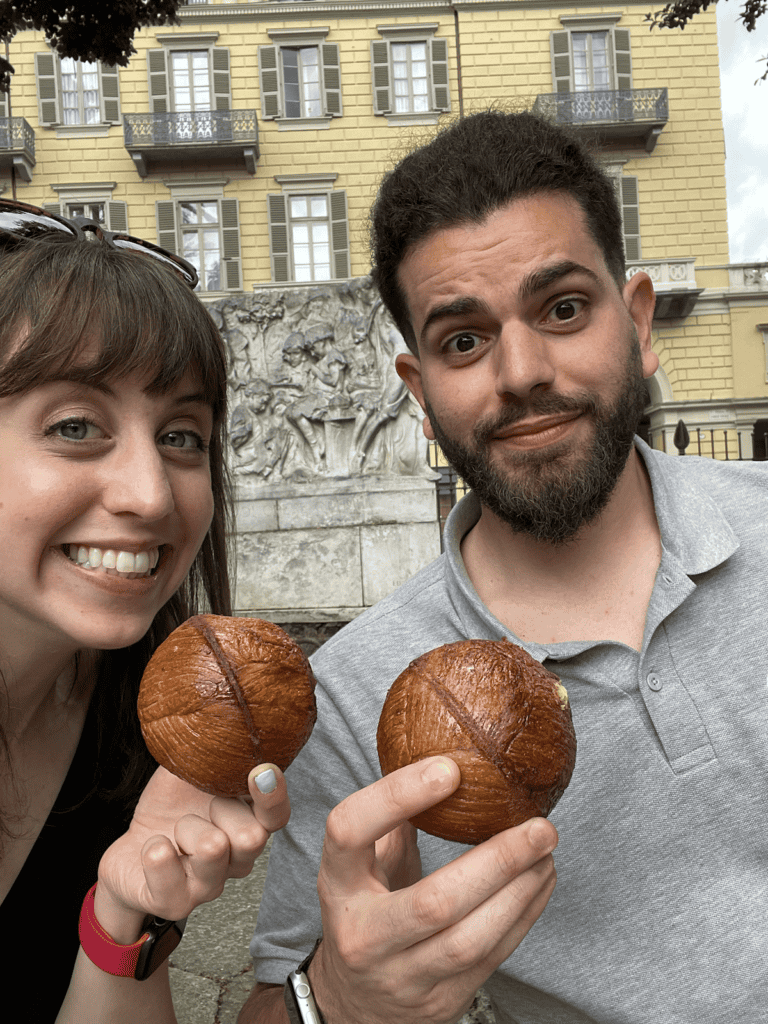 two people smiling at the camera holding sphere croissants