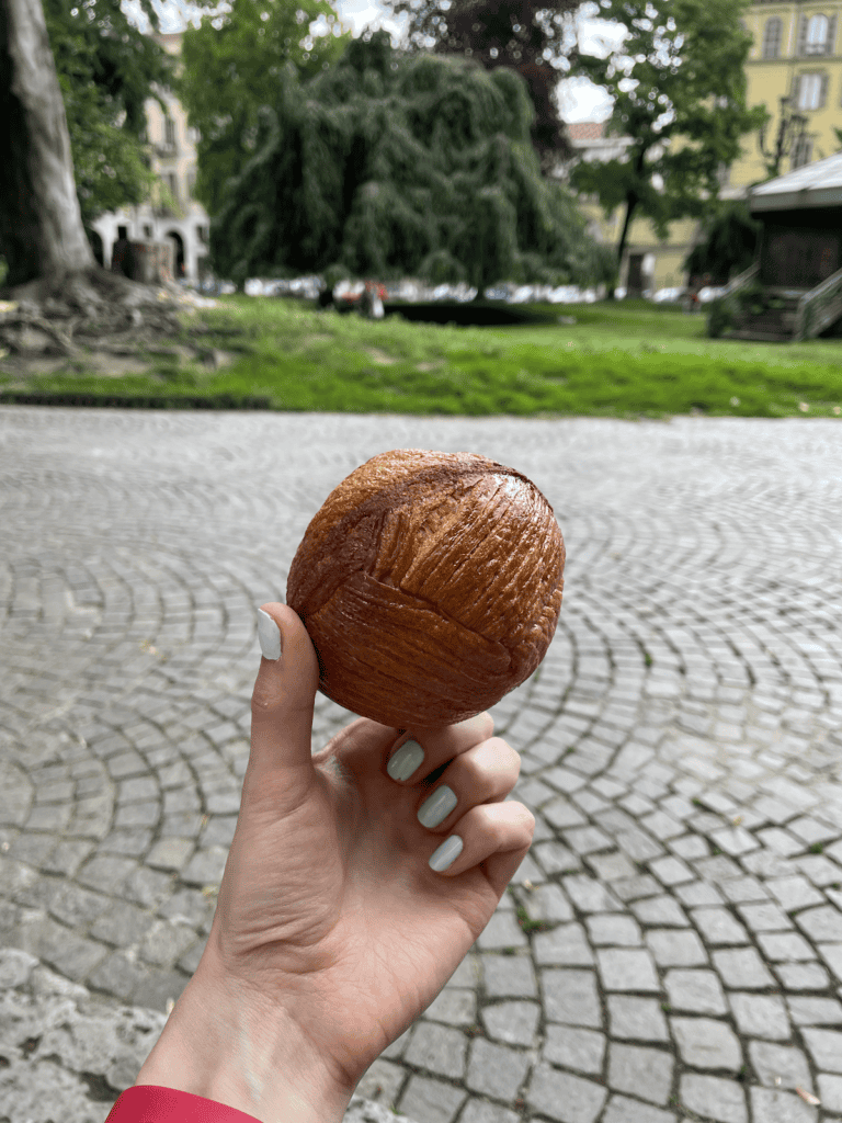 a hand holding a sphere croissant in a park