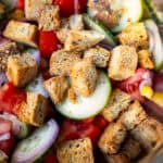 a close-up of panzanella ingredients like bread, cucumber, tomato, and shallot