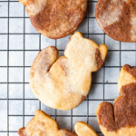 tri-colored cookies in the shape of a cat on a black cooling rack